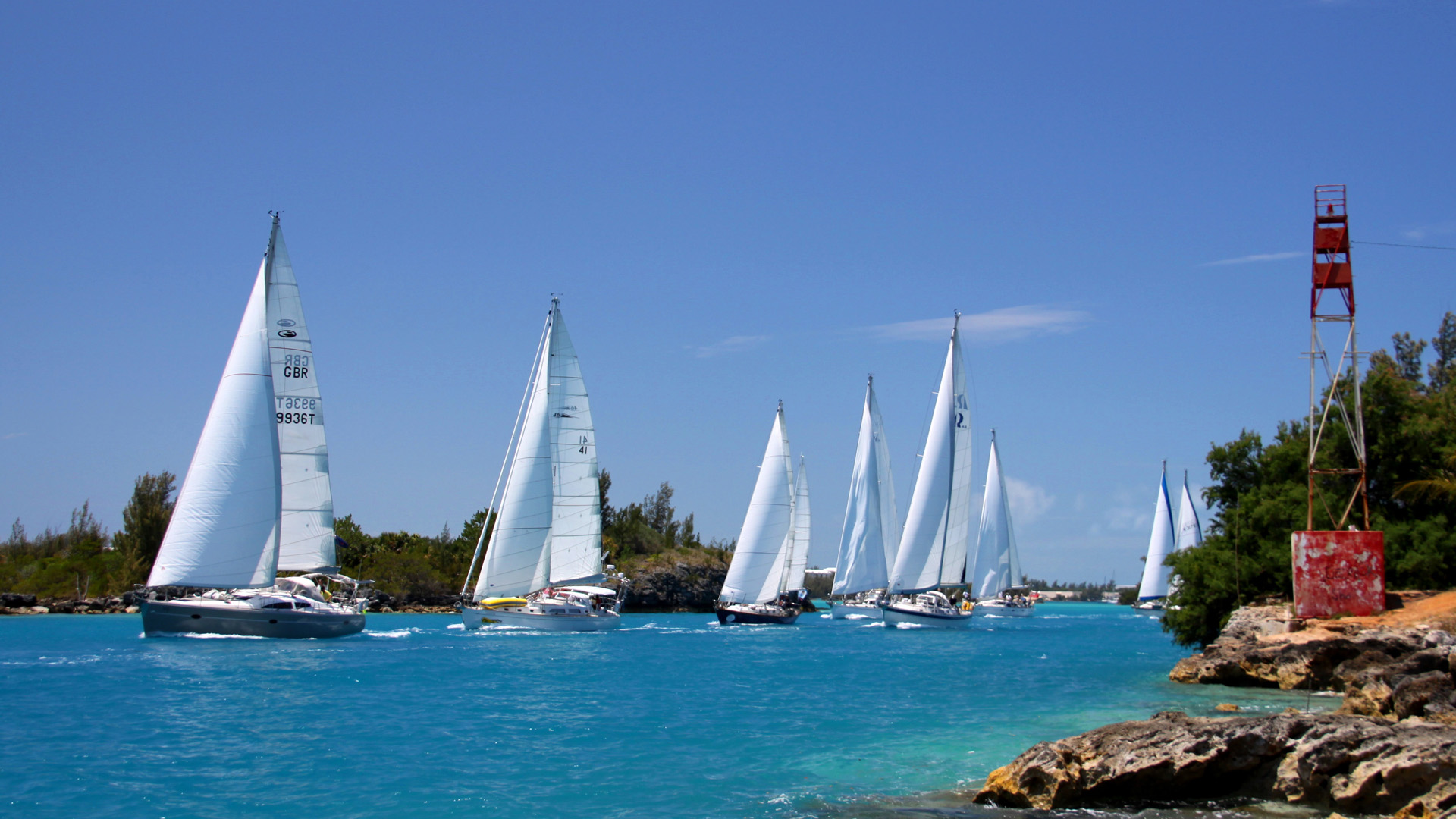 With a blue sky and blue sea, ARC Europe yachts sail through The Cut in Bermuda