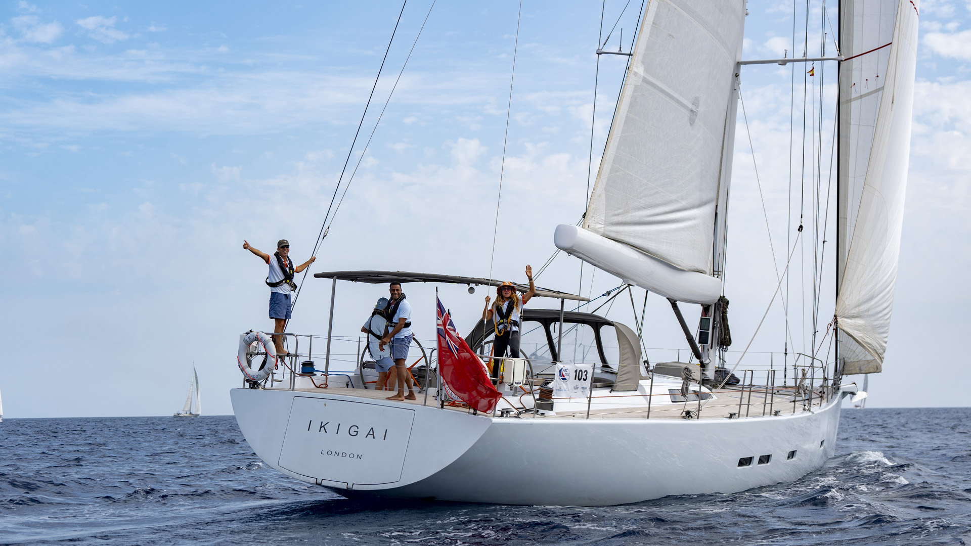 Yacht Ikigai sailing away from Las Palmas at the start of ARC 2024 with the crew members waving