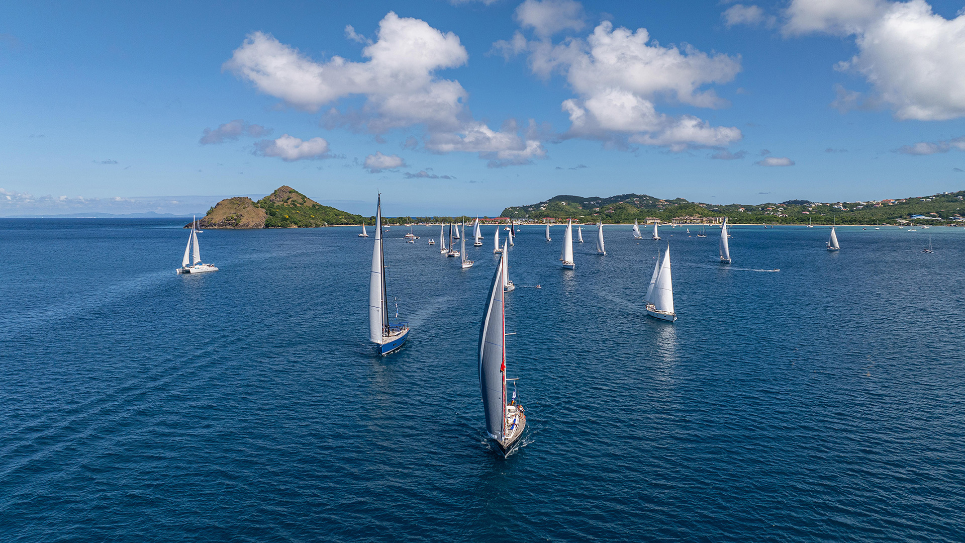 Yachts sailing out of Rodney Bay Saint Lucia with Pigeo Island in the background at the start of World ARC 2025