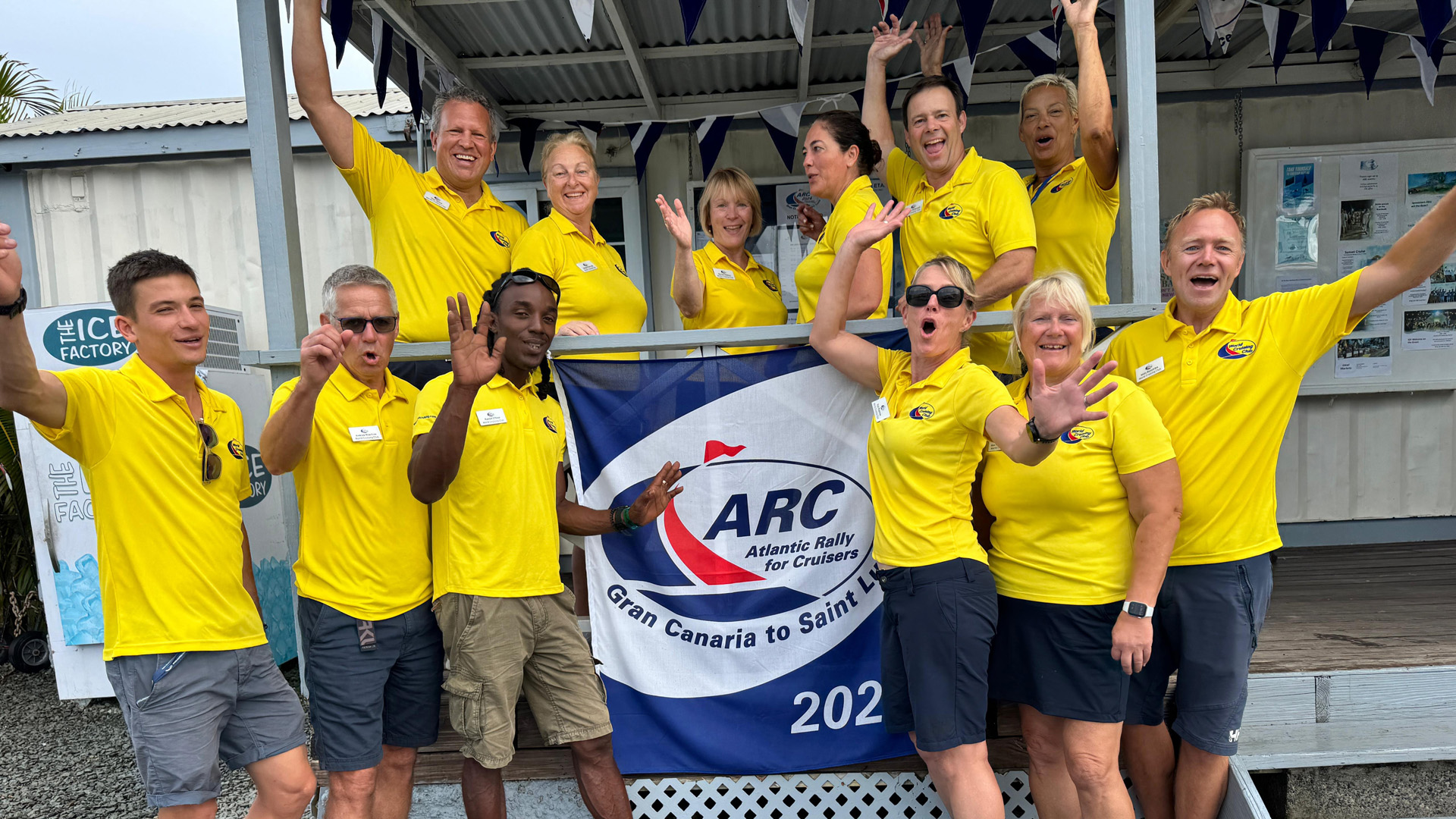 The World Cruising Club yellow shirt team for ARC 2024 waving and cheering