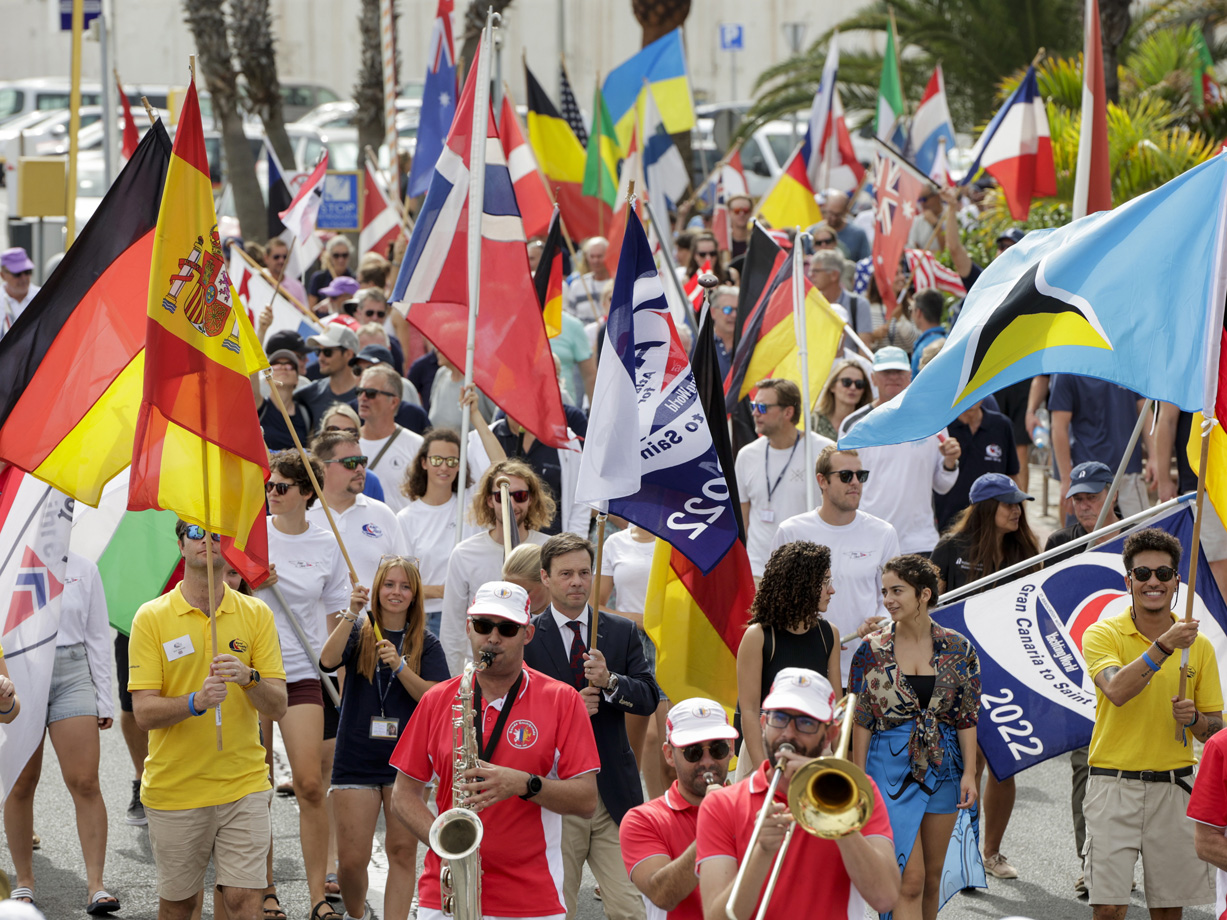 A colourful parade of people waving national flags and a brass band at the opening ceremony parade for ARC 2022 in Las Palmas