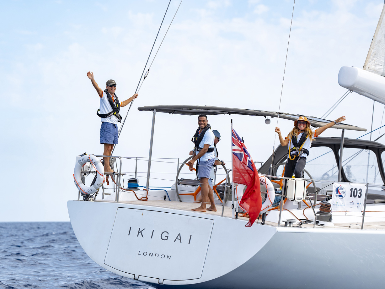Crew members wave from the deck of yacht Ikigai at the start of ARC 2024 from Las Palmas