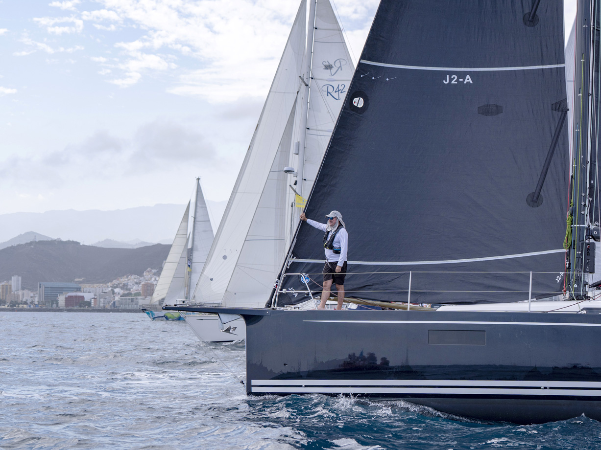 A crew man on the bow of an ARC racing division yacht with carbon sails