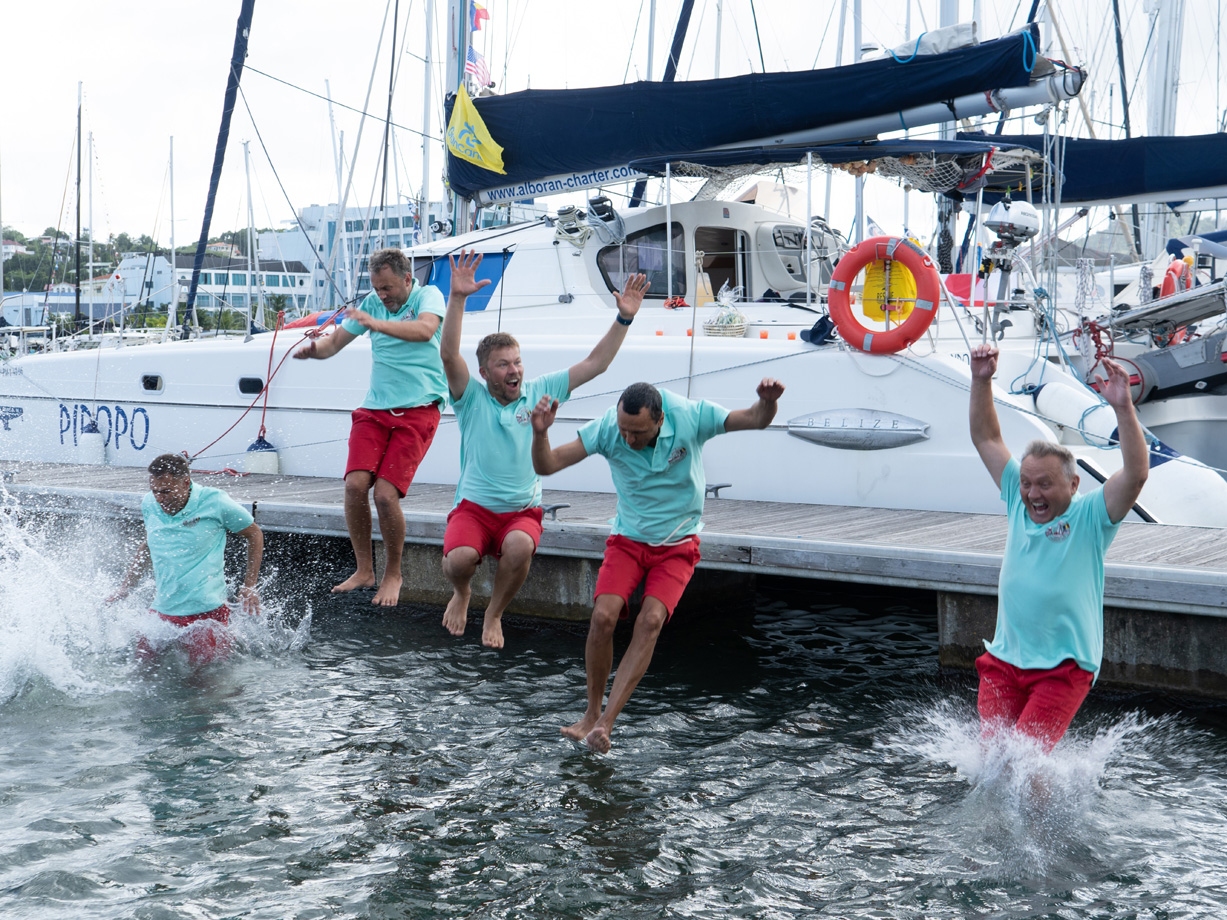 Men in t-shirts and shorts jump into the water from yacht Piropo Primero in Rodney Bay Marina