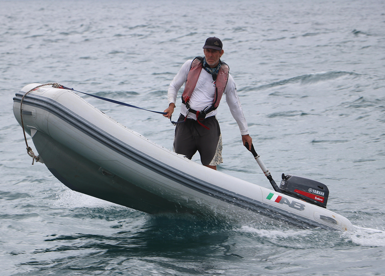 ARC finish line photographer Tim Wright standing up in his little grey dinghy