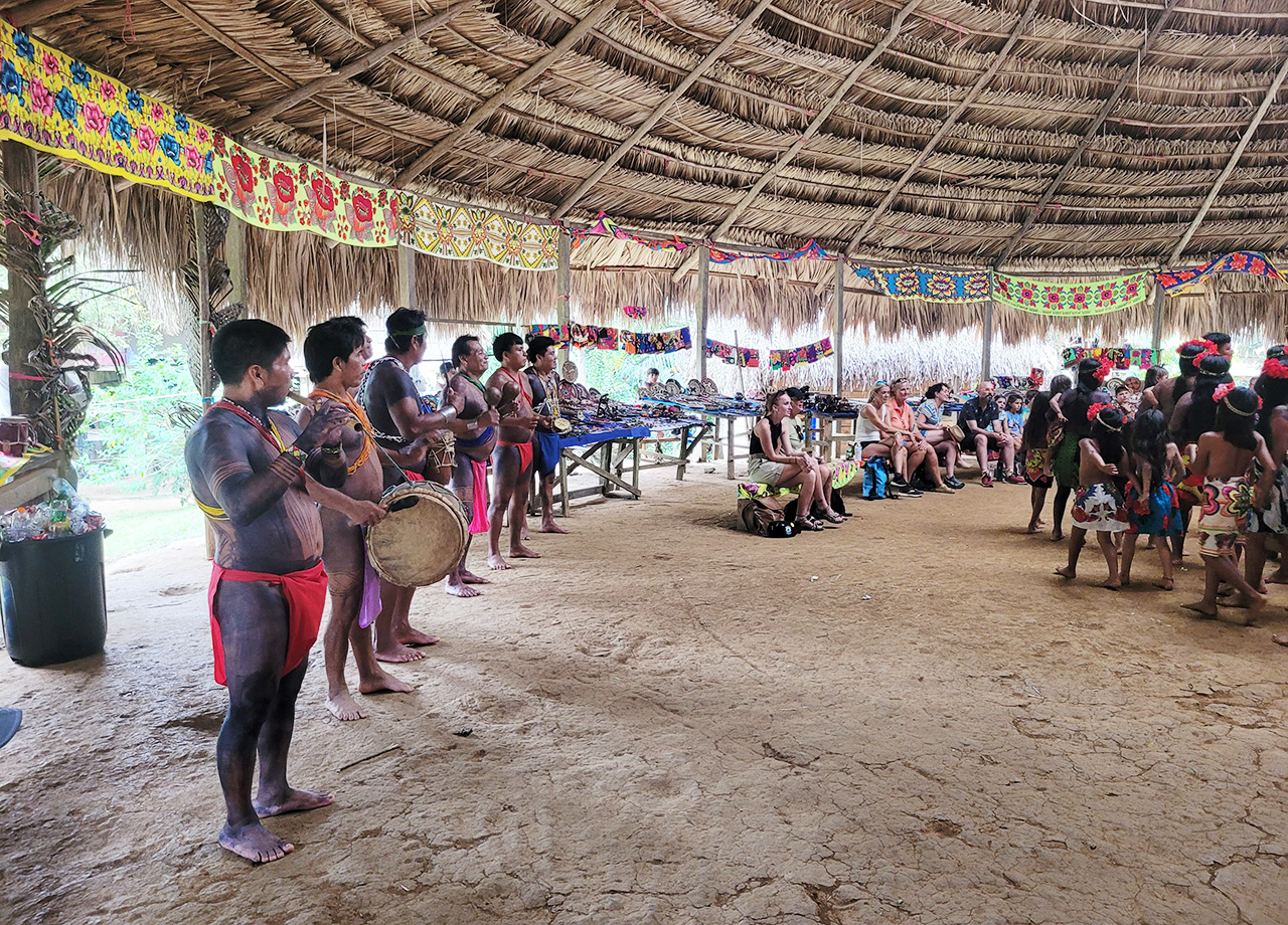 Embera Indian musicians play instruments inside a large wood and palm building in Panama