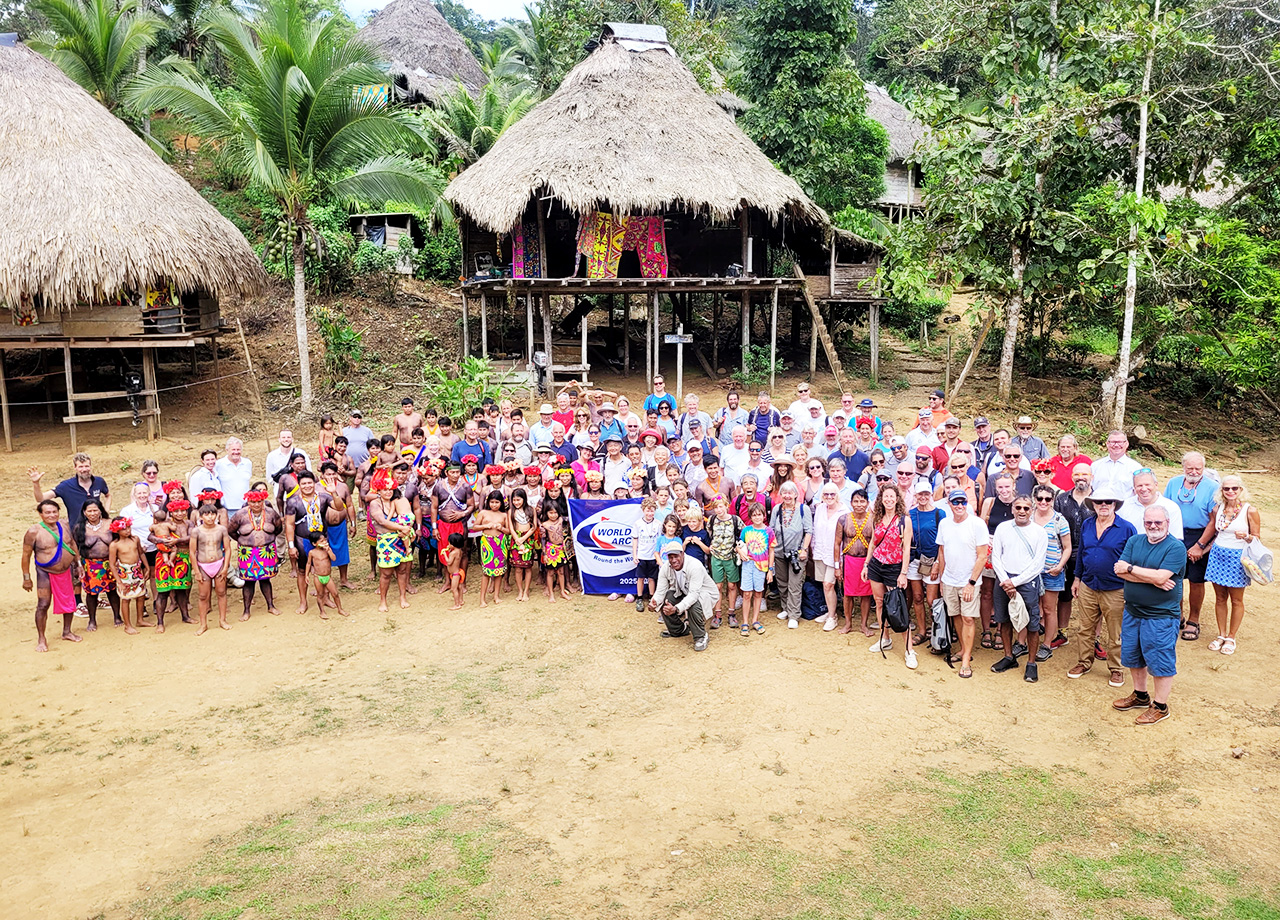 A large group of World ARC sailors and Embera Indians stand in the Embera village of wood and thatch stilt houses in the Panama jungle