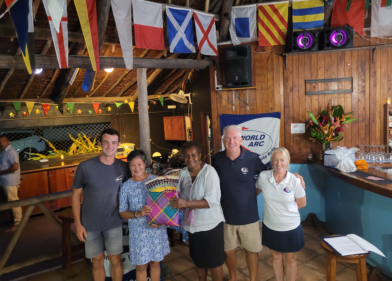 With colourful flags hanging above, the men and women crew from World SARC yacht Alegria post with their prize