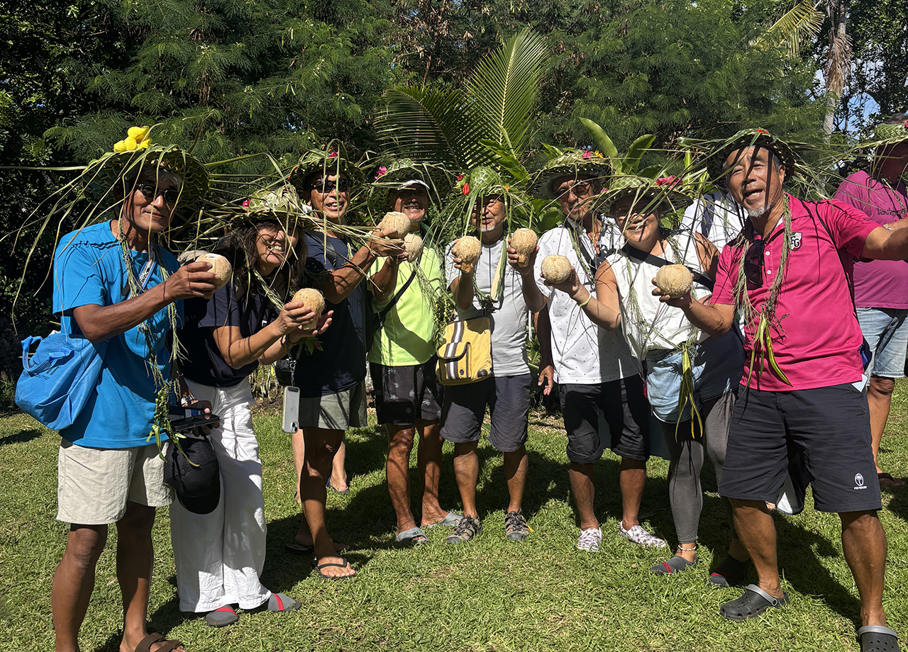 A group of Japanese people wearing green palm hats and holding coconuts in Tanna
