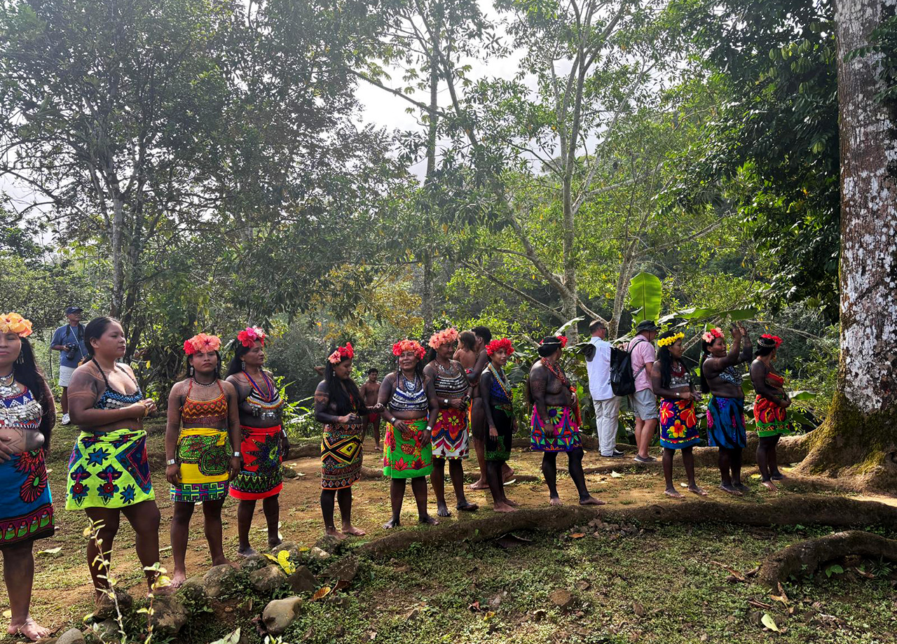 Embera men women in colourful clothes with flowers in their hair stand in the Panama rain forest