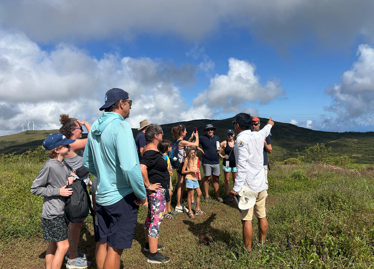 People of all ages listen to a guide in the green mountains of La Galapaguera national park