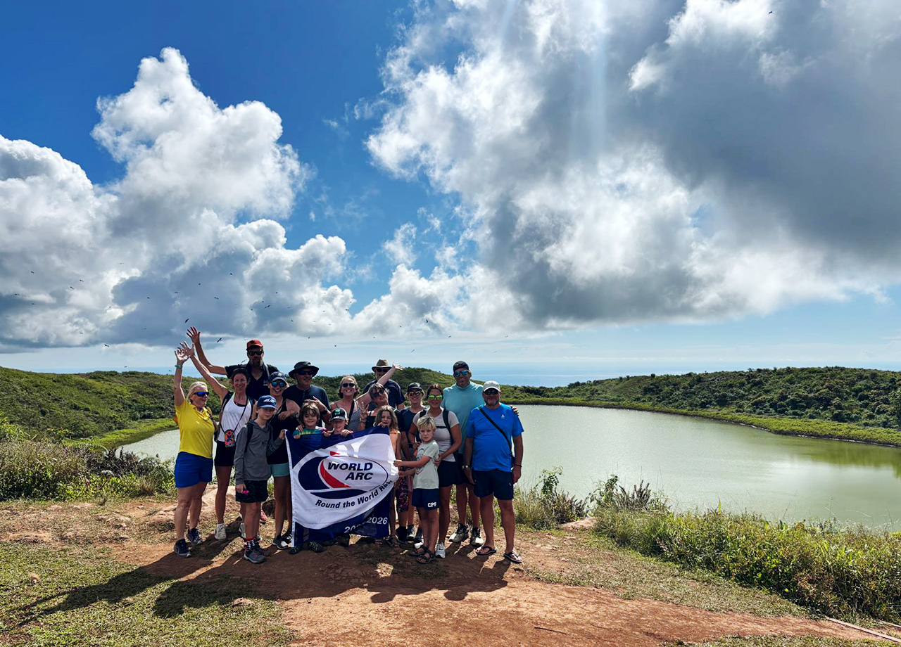 World ARC sailors hold up a rally flag at El Junco Lagoon on a tour of San Cristobal, Galapagos