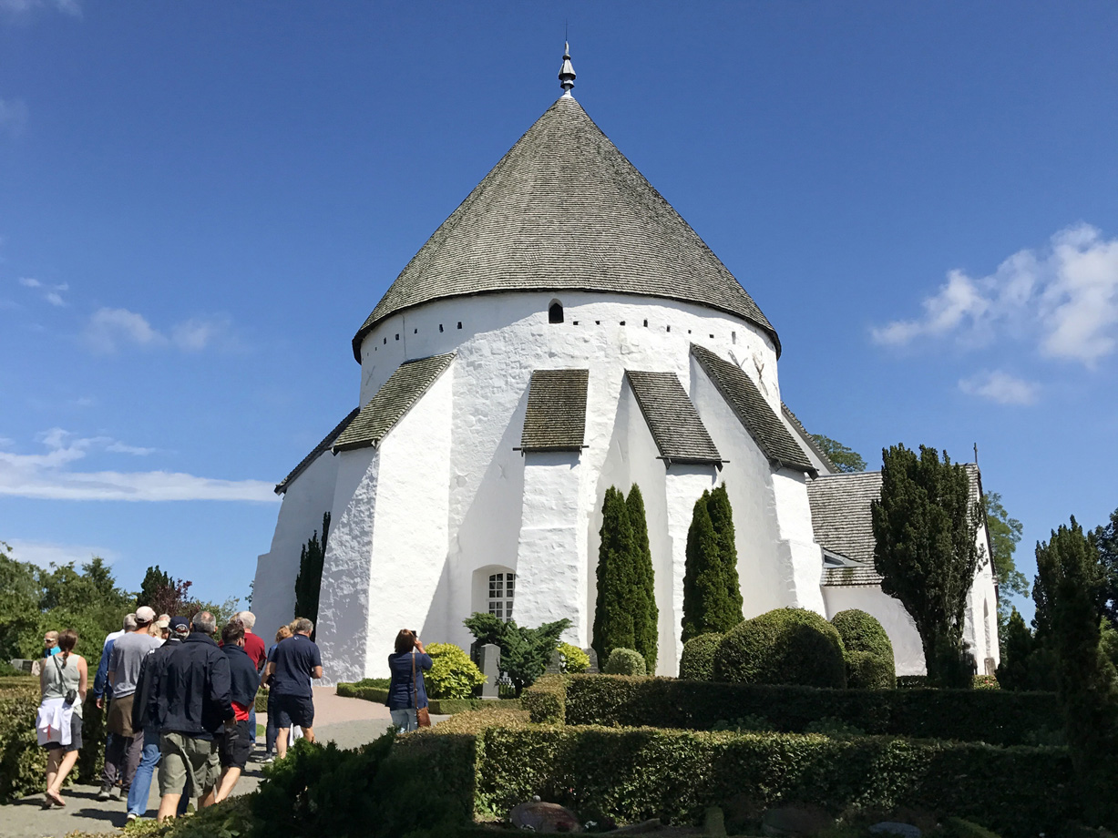 A round white building with multiple stone butresses, all capped with a slate conical roof