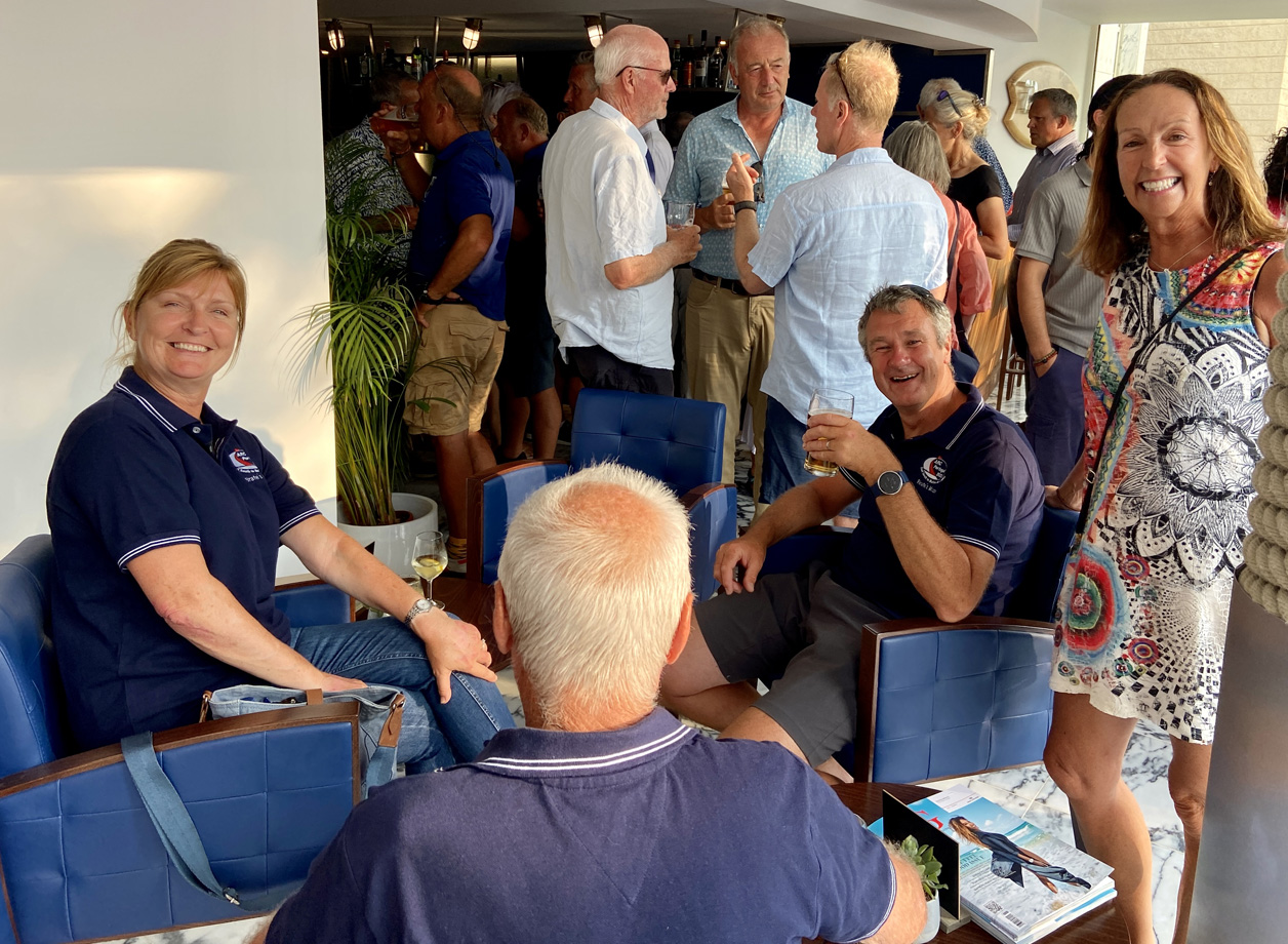 A group of seated and standing ARC Portugal sailors in a yacht club bar