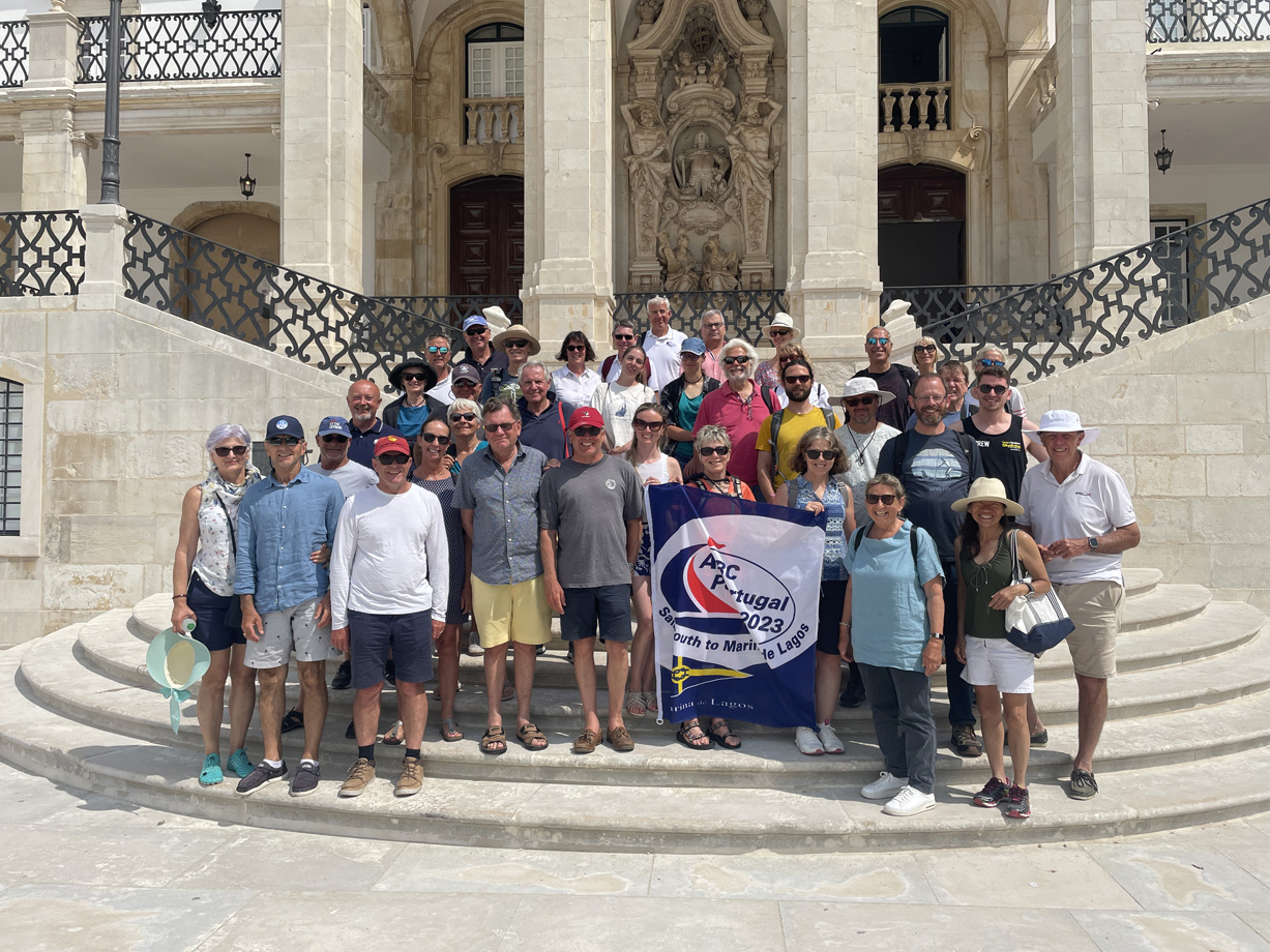 ARC porugal sailors holding a flag gather on the steps on a historic stone building in Coimbra