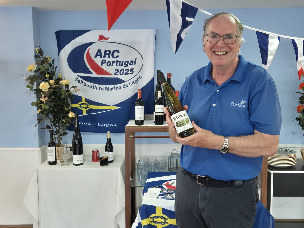 A man wearing a blue polo shirt holds a bottle wine as a prize at the ARC Portugal prizegiving