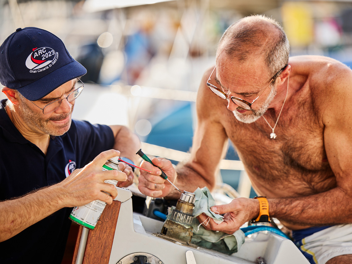 Two men carefully take apart a winch onboard yacht Lady Elenora before ARC 2023