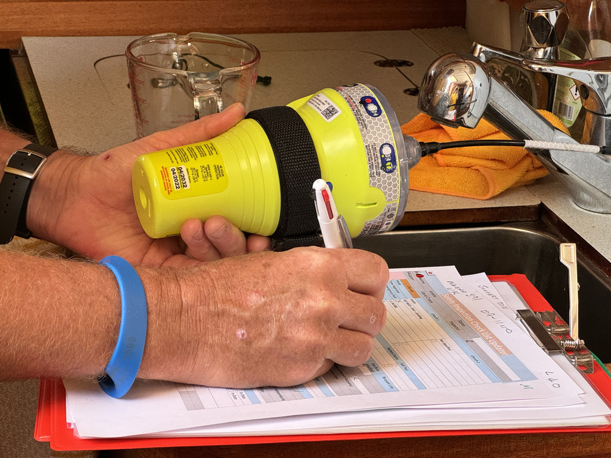 A man writes down the details of a yellow EPIRB beacon he holds in his hand