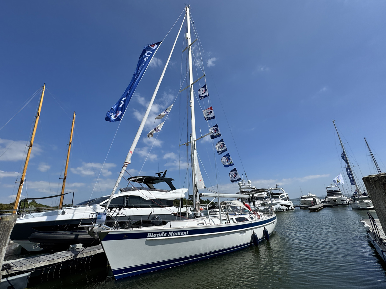 Hallberg Rassy yacht Blonde Moment docked in a marina flying lots of ARC flags
